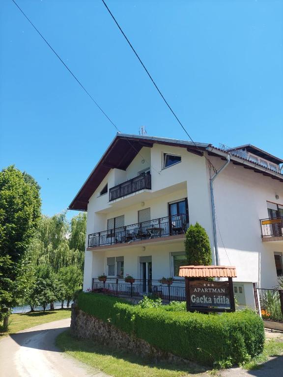 a white building with a sign in front of it at Gacka idila 2 in Otočac
