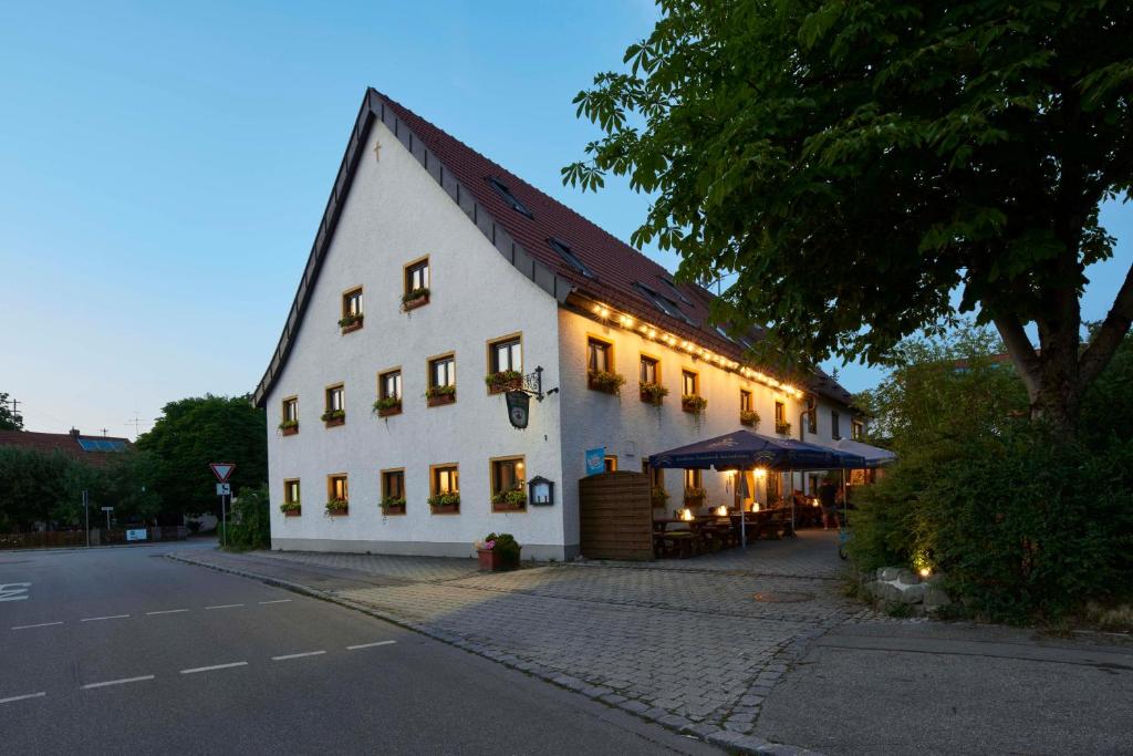 a large white building with a restaurant on a street at Gasthaus Alter Wirt in Oberneuching
