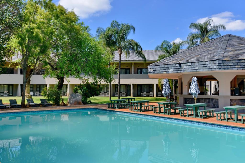 a swimming pool in front of a hotel at Pilanesberg Hotel in Boshoek