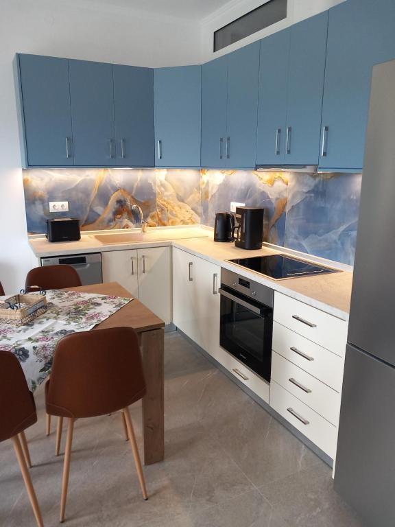 a kitchen with blue cabinets and a table with chairs at Thalassoudis-House 2 in Agios Nikolaos