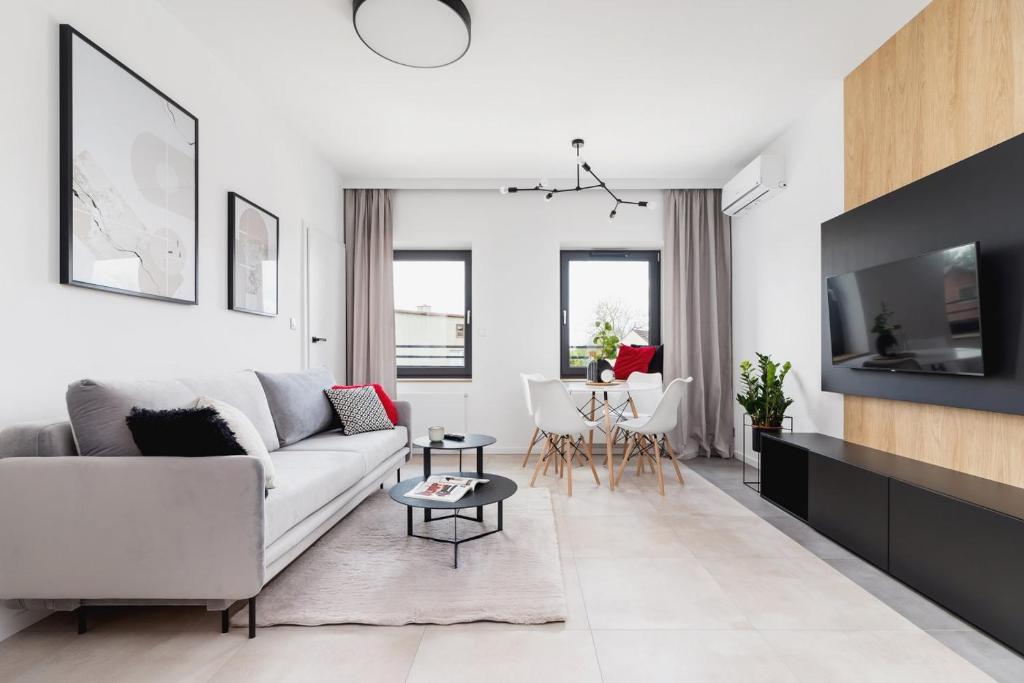 a living room with a white couch and a tv at Apartamenty EN Zator in Podolsze