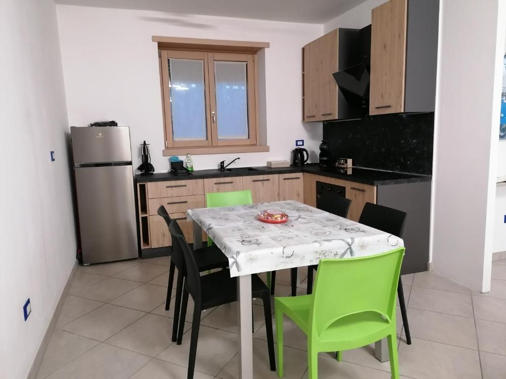 a kitchen with a table with chairs and a refrigerator at Appartamento da Nonna Anna in Montagna in Valtellina