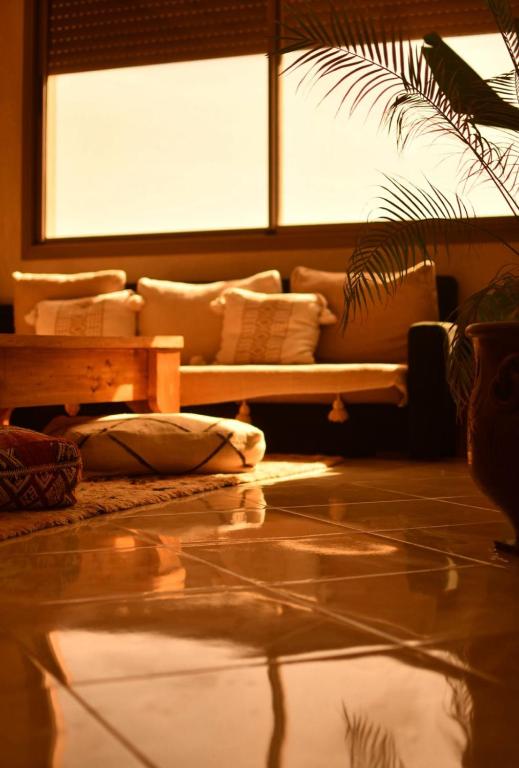 a living room with a couch in front of a window at Adrenalin Surf House in Tamraght Ouzdar