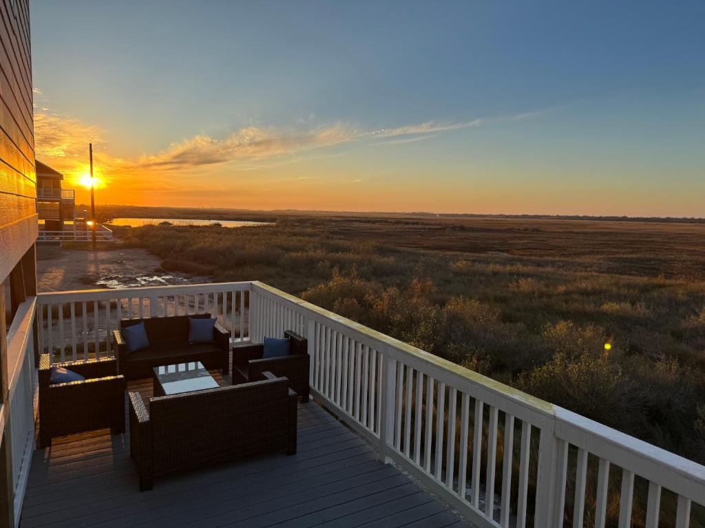 a sunset on a deck with chairs and tables at Beach House with Breathtaking Sunsets - Perfect for Couples and Families! in Bolivar Peninsula