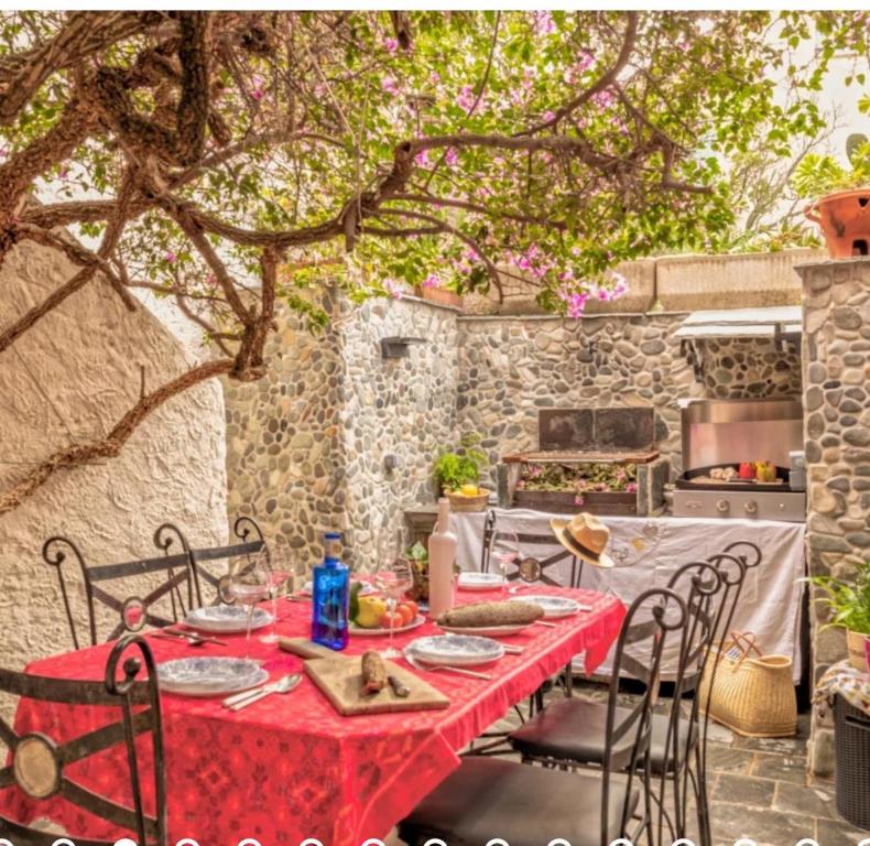 a table with a red tablecloth and chairs under a tree at Villa Emmanuella in Centuri