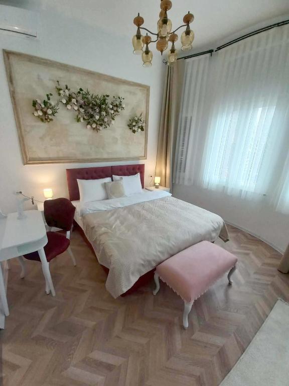 a bedroom with a bed and a table and a painting at Villa Korzo in Bitola