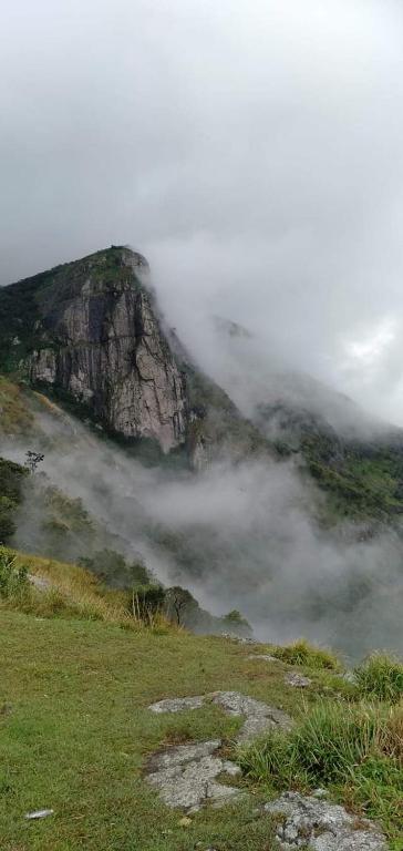 a mountain in the fog on a grassy hill at Fogveilhomestay in Idukki