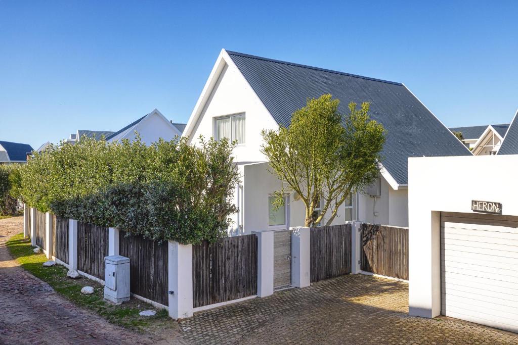 a white house with a wooden fence at HERON at Cape St Francis Lifestyle Estate in Cape St Francis