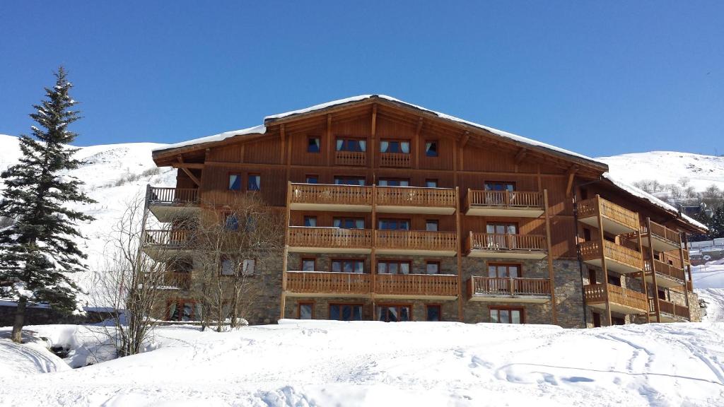 a large wooden building in the snow at Les Airelles A21 in Les Menuires