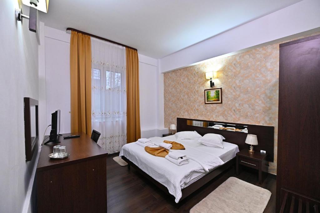 a bedroom with a bed and a desk and a television at Hotel Magic GT Trivale in Piteşti
