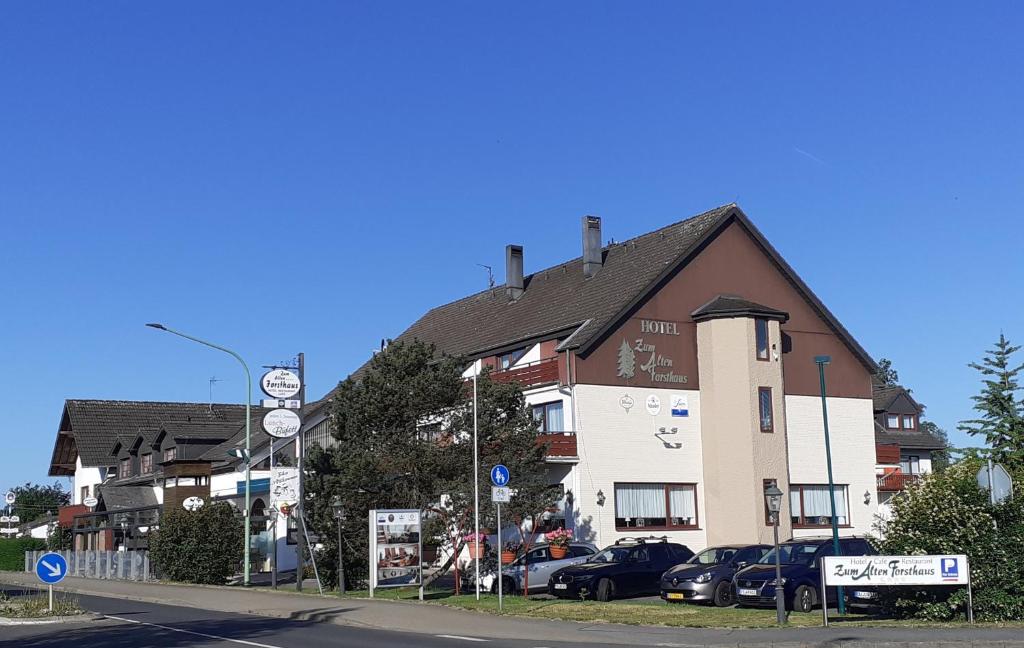 a building with cars parked in a parking lot at Land-gut-Hotel Zum alten Forsthaus - Aufladestation für Elektroautos in Hürtgenwald