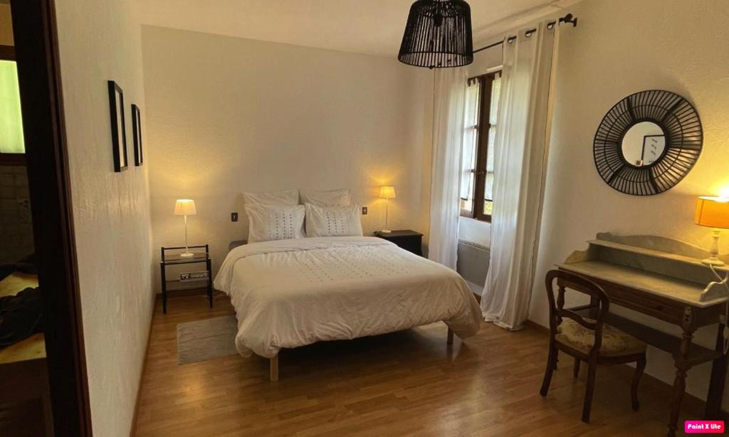a bedroom with a bed and a table and a mirror at Chambre d'hôte domainedesthermesgap in La Celle-sous-Gouzon