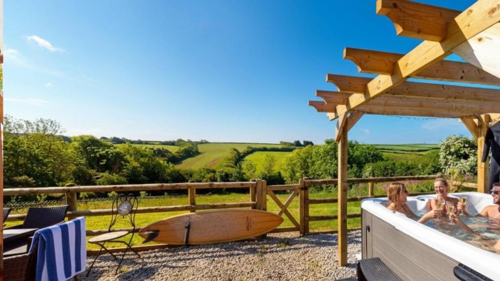 a hot tub on a deck with a surfboard at Georgeham Sweet Pea Cottage in Georgeham
