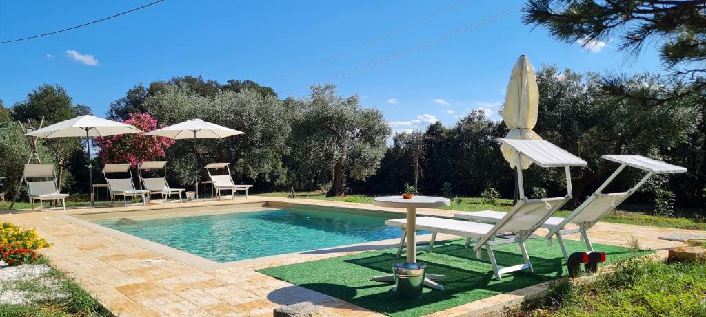 ein Pool mit Stühlen, einem Tisch und einem Sonnenschirm in der Unterkunft Villa Morea-Relax in piscina in Putignano