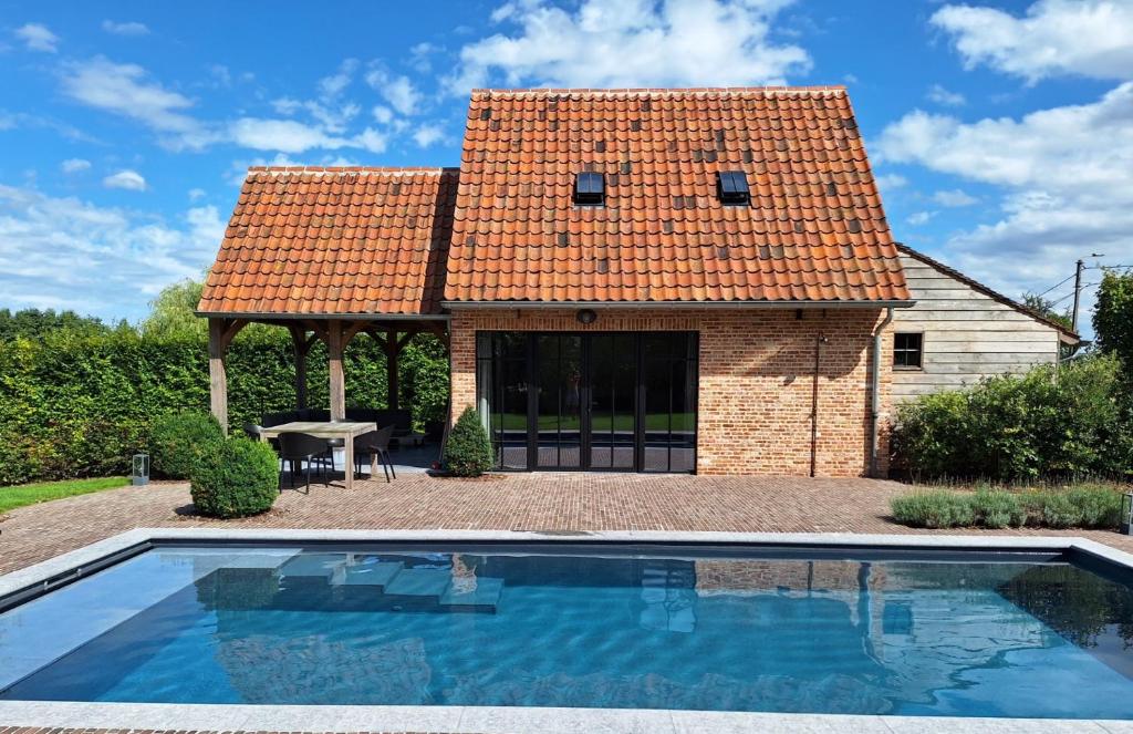 a house with a swimming pool in front of a building at Gezellig huisje met zwembad en sauna in Ellezelles - Bellezelles in Ellezelles