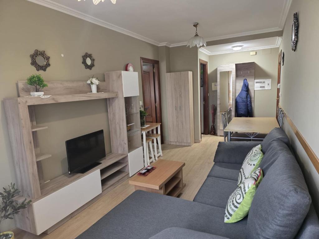 a living room with a blue couch and a tv at Apartamentos Camino Inglés 3 in O Mesón Do Vento 