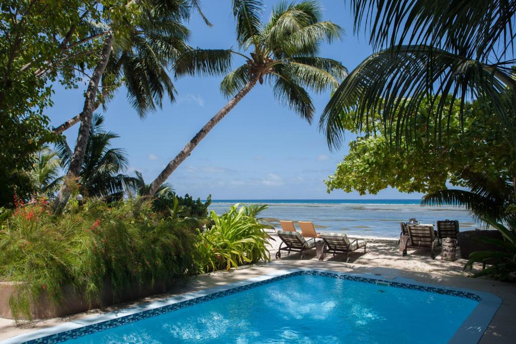 a swimming pool with the beach in the background at Le Repaire - Boutique Hotel & Restaurant in La Digue