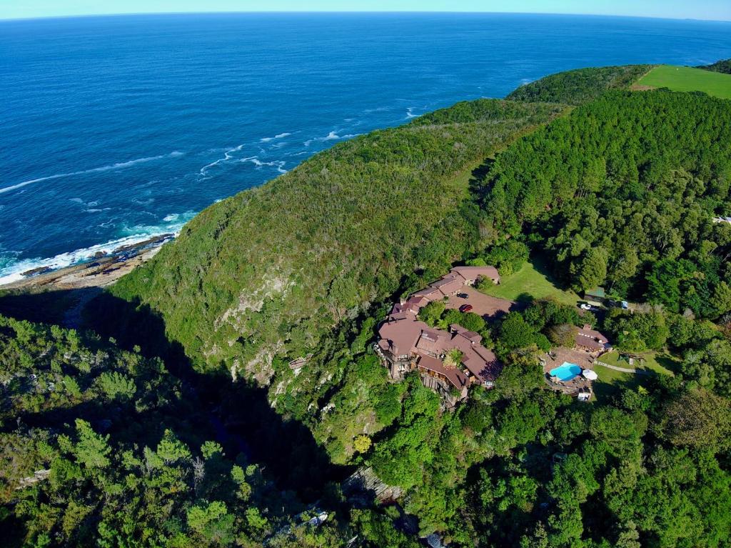 an aerial view of a house on a hill next to the ocean at The Fernery Lodge & Spa in Stormsrivier