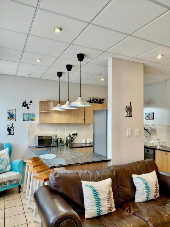 a living room with a leather couch and a kitchen at The Tipsy Expat - Paarl - Self Catering Apartment in Paarl