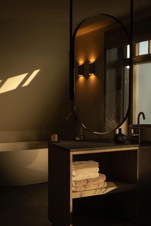 a bathroom with a mirror and a sink and a tub at Boutique Hotel AEST Terschelling in Hoorn