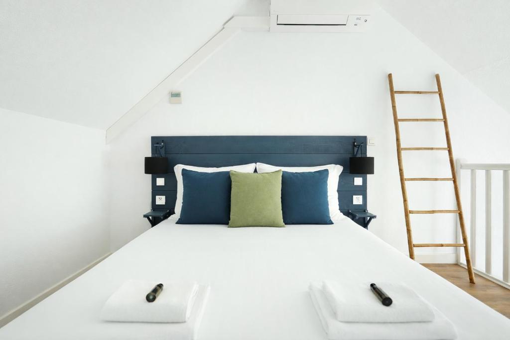 a bedroom with a white bed with a ladder at Les Lilas Serviced Apartments in Les Lilas