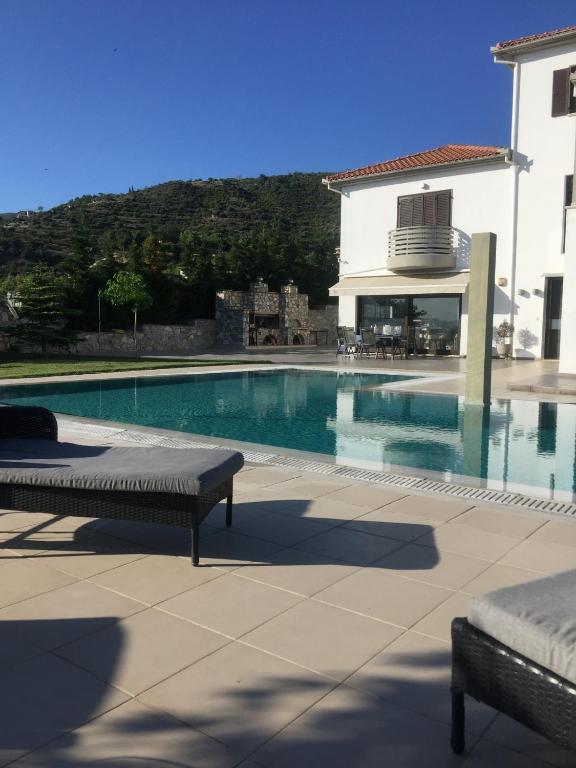 a swimming pool with two benches next to a building at VILLA KTIMA MELINA Pelio ΒΙΛΑ ΜΕ ΠΙΣΙΝΑ ΒΟΛΟΣ ΠΗΛΙΟ in Álli Meriá