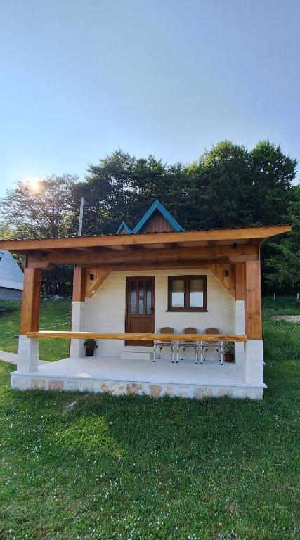 a small cabin with a table and chairs in the grass at Koliba in Žabljak