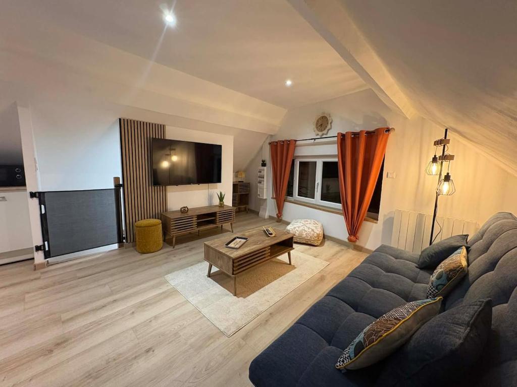 a living room with a blue couch and a tv at Appartement douillet in Haspres