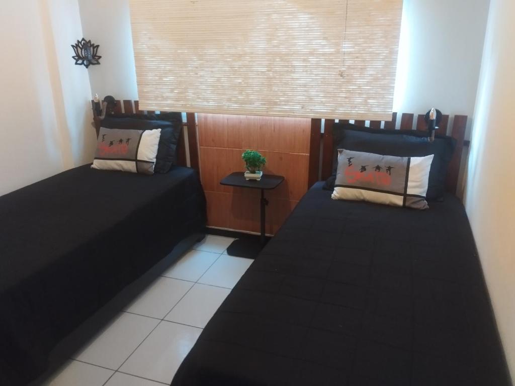 two beds in a small room with a window at UniversiFlat in Ponta Grossa