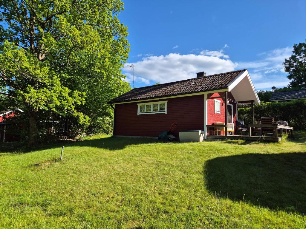 a small red house in a yard next to a yard at Ferienhaus Stensjö in Holmsjö