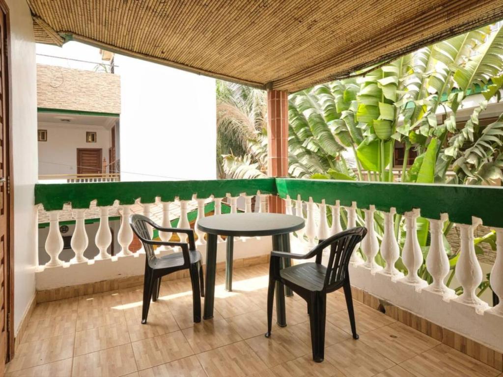 a table and chairs on a balcony with plants at Case Africaine Confort Terrasse Accès Plage in Mbour