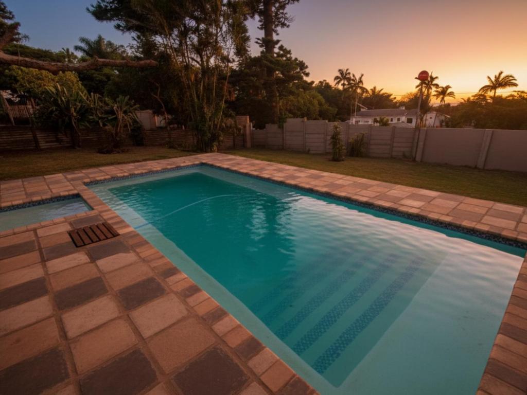 a swimming pool in a yard with a sunset at Picasso - Zur See in Ballito