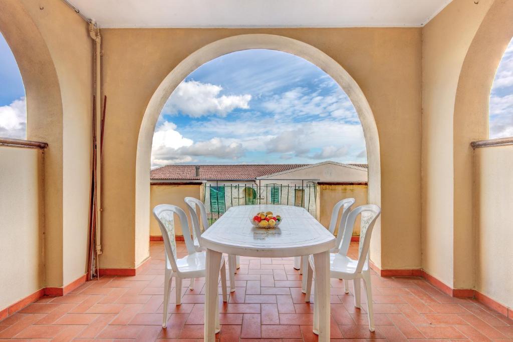 a dining room with an archway and a white table and chairs at Appartamento Orchidea in Capoliveri