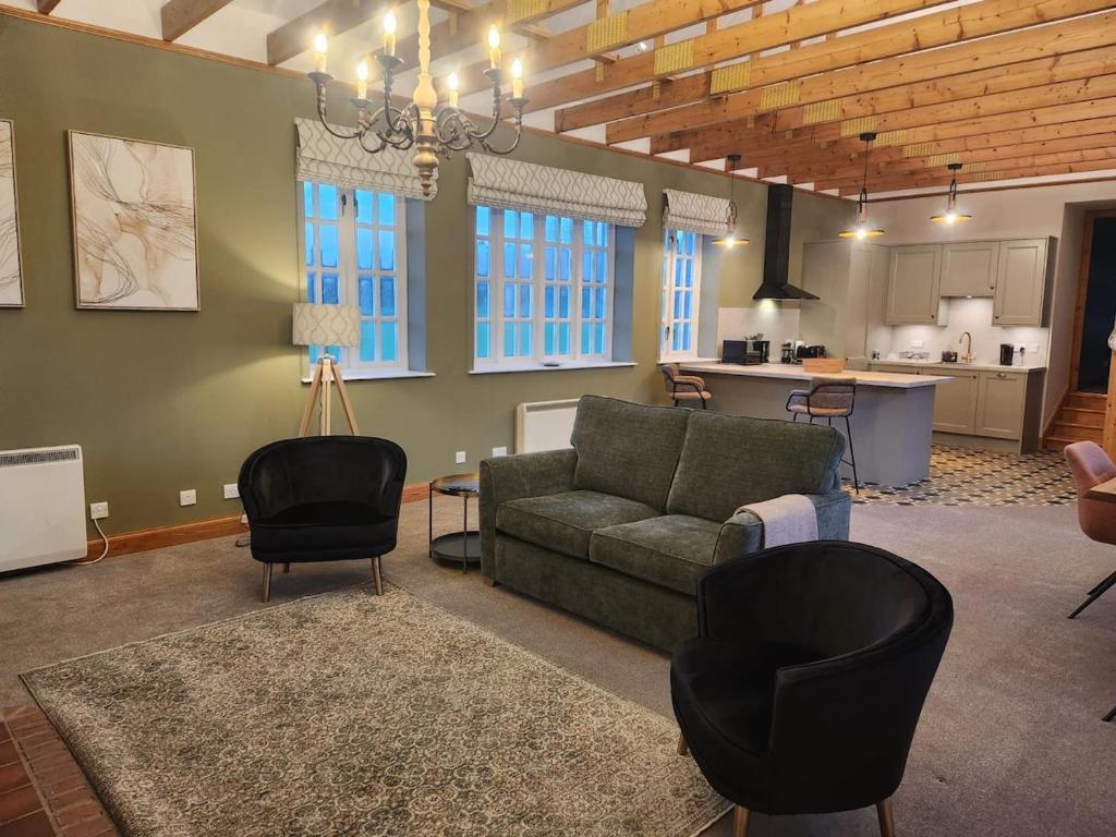 a living room with a couch and chairs and a kitchen at Recently refurbished former art studio in Rothiemay Station
