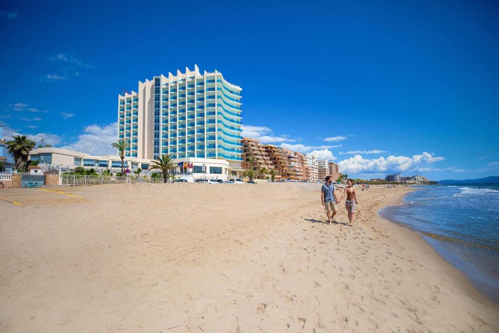 a man and woman standing on the beach at Hotel Servigroup Koral Beach 4 Sup in Oropesa del Mar