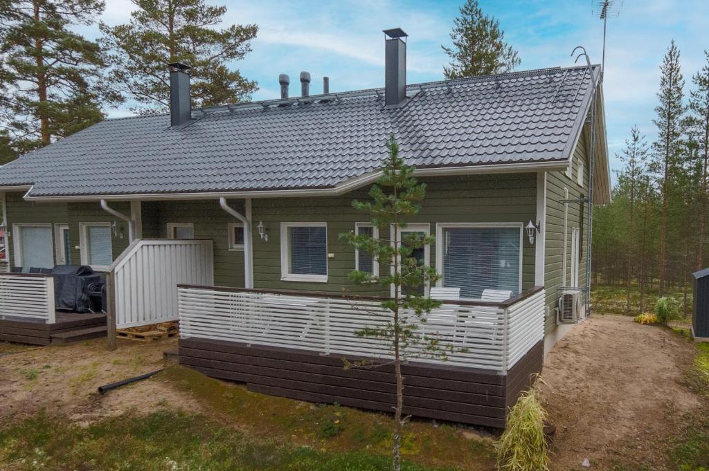 a small green house with a white porch at Villa Luoto A Stylish semi-detached house Incl AC, Sauna, Terrace in Kalajoki