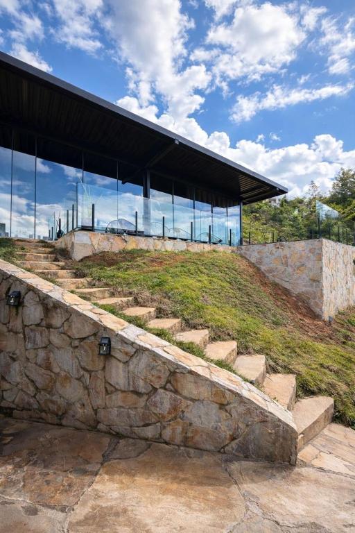 a building with a stone wall and glass at Loft Vilas Boas in Nova Lima
