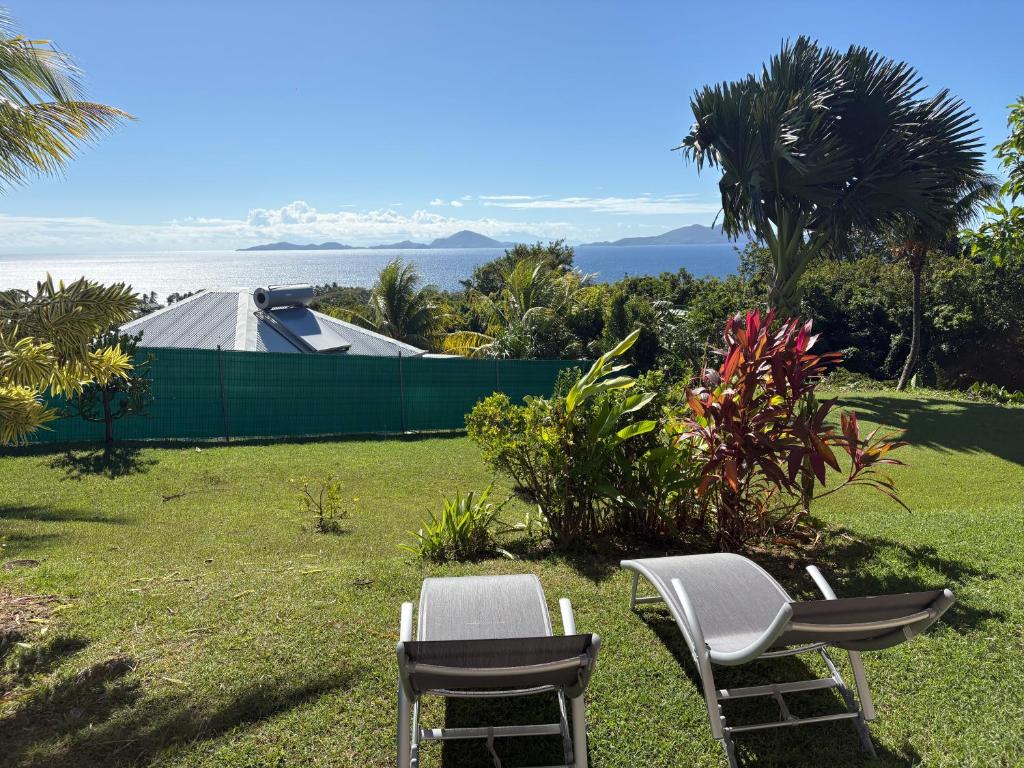 two chairs and a tent in a yard with the ocean at Belle vue de Grande Anse in Trois-Rivières