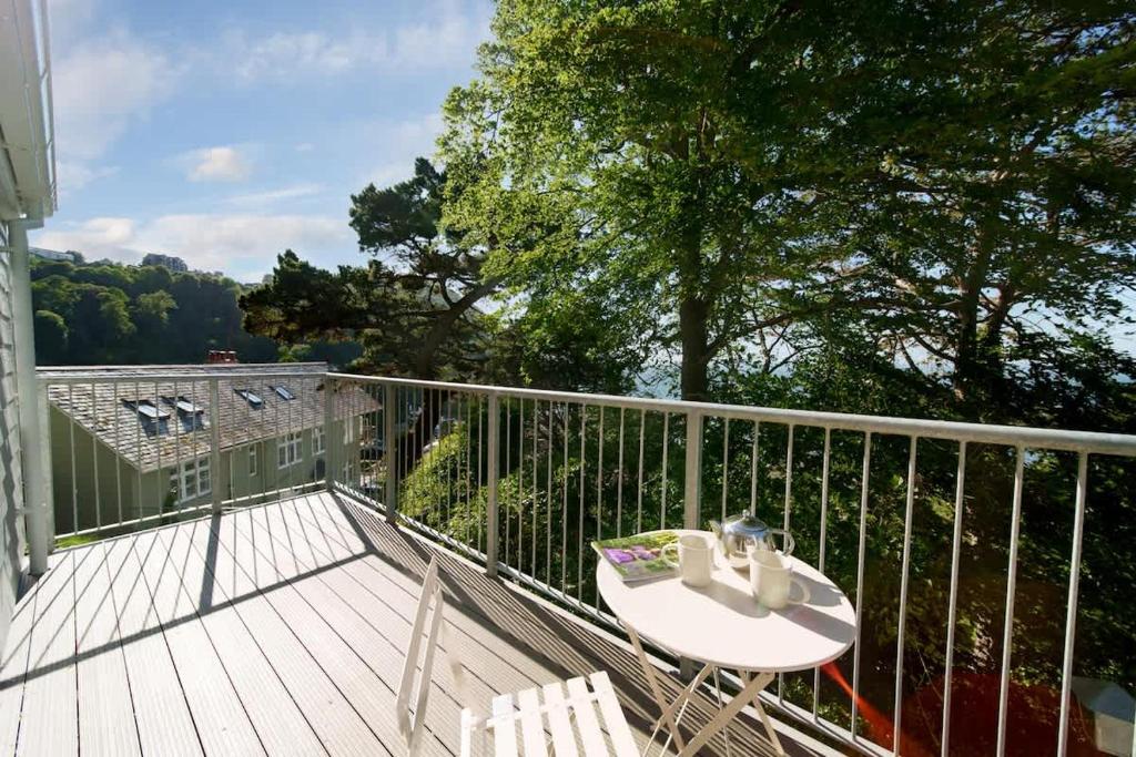 a balcony with a table and chairs on a deck at Tree Top - Perfect Apartment For Relaxing Getaway, Balcony, Parking in Lynmouth