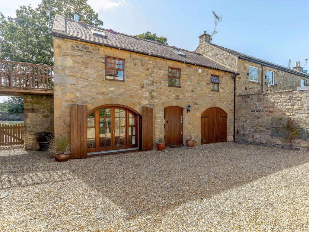 an old stone house with wooden doors and a balcony at 2 Bed in Hexham oc-88443 in Acomb