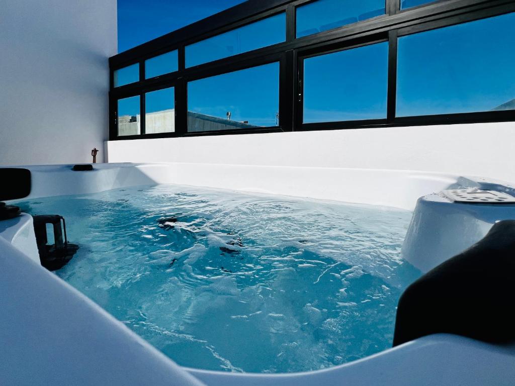a tub filled with blue water next to a window at Atlantic Green 3 Apartment, Terrace, Solarium and Spa in El Cotillo