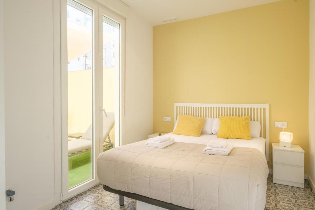a bedroom with a bed with yellow pillows and a window at Marvellous Apt with a Large Private Terrace in Valencia