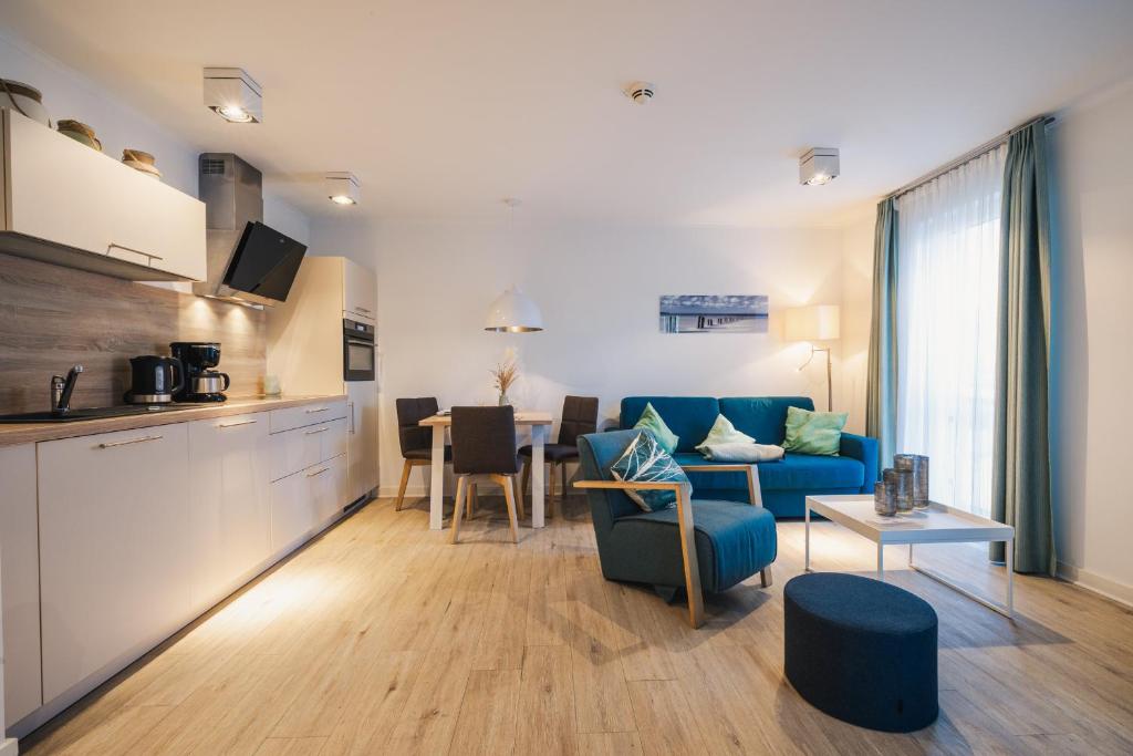 a living room with a blue couch and a kitchen at Am Park 14 in Prerow