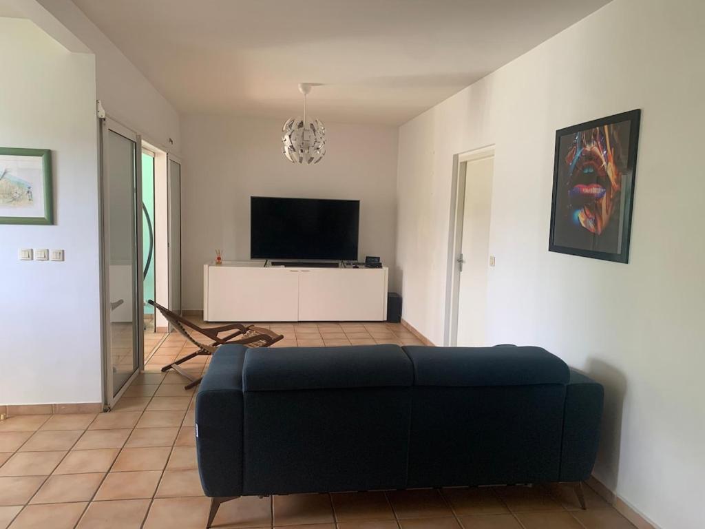 a living room with a couch and a flat screen tv at Chic, bright and quiet in Baie-Mahault