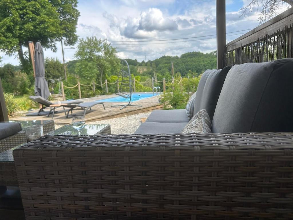 a patio with a couch and a pool in the background at Le Blanc Spa in Nanteuil-en-Vallée