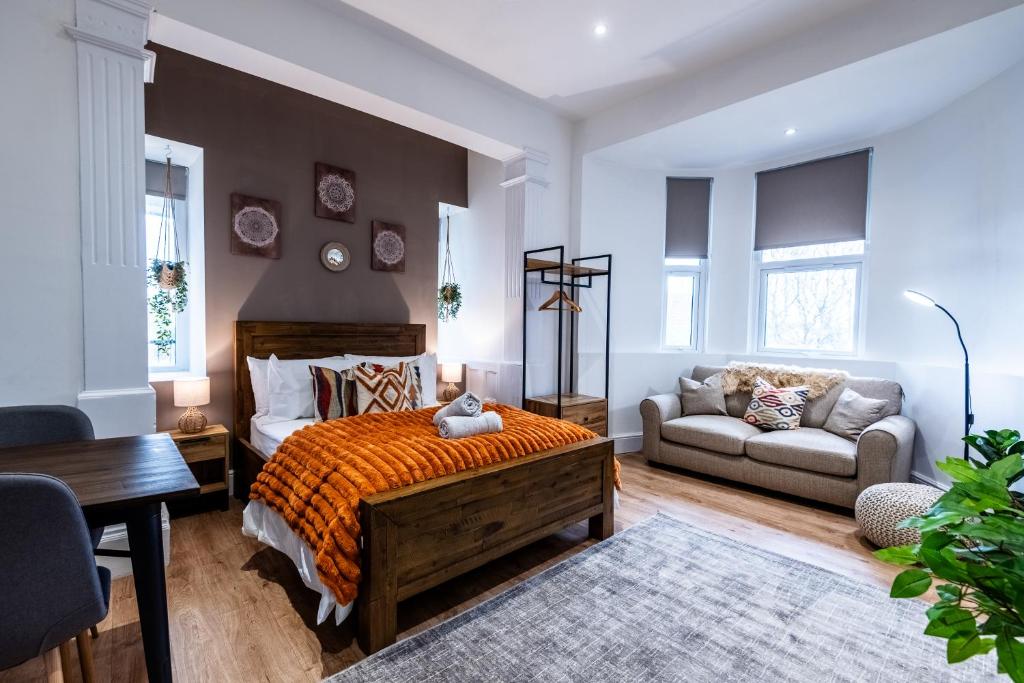 a bedroom with a bed and a couch and a desk at Glan Neigr Apart-Hotel by Guestz in Rhosneigr