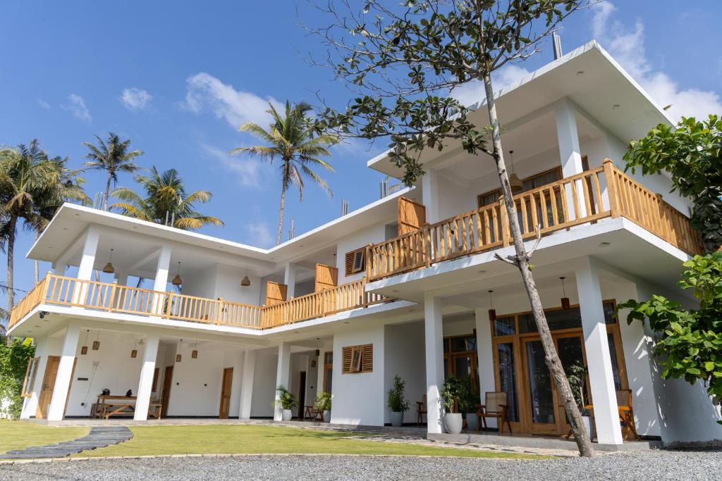 a large white house with a balcony at Beach House by Unrushed in Welhengoda