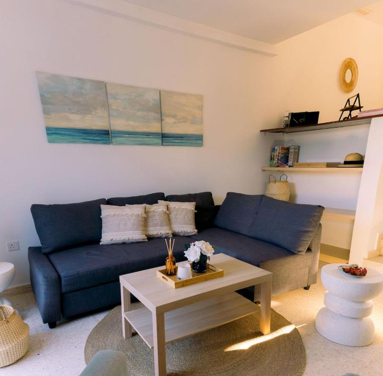 a living room with a blue couch and a coffee table at Kymo Fig Tree Bay House in Protaras