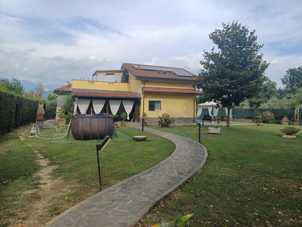 a house with a walkway in front of a yard at Charme rustico con ampio giardino e piscina con due camere in Carrara