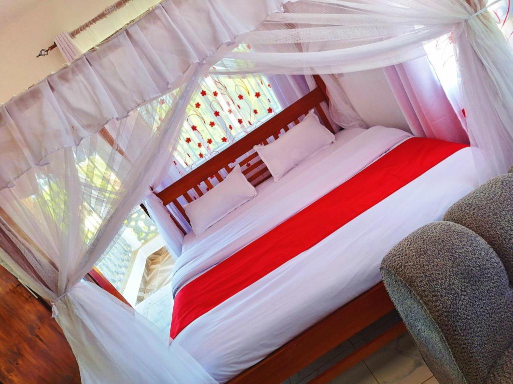 a bedroom with a red and white bed with a canopy at Adventure studio apartment in Mtwapa